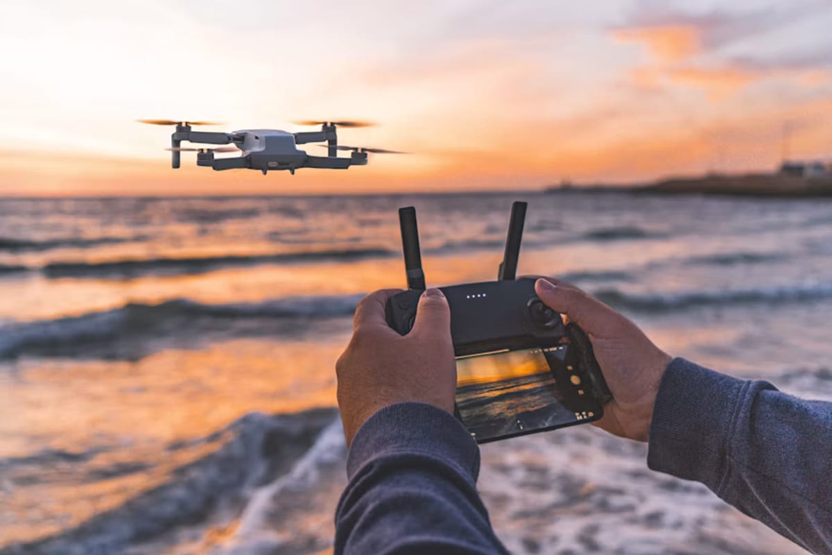 A camera drone flying above the coast at sunset