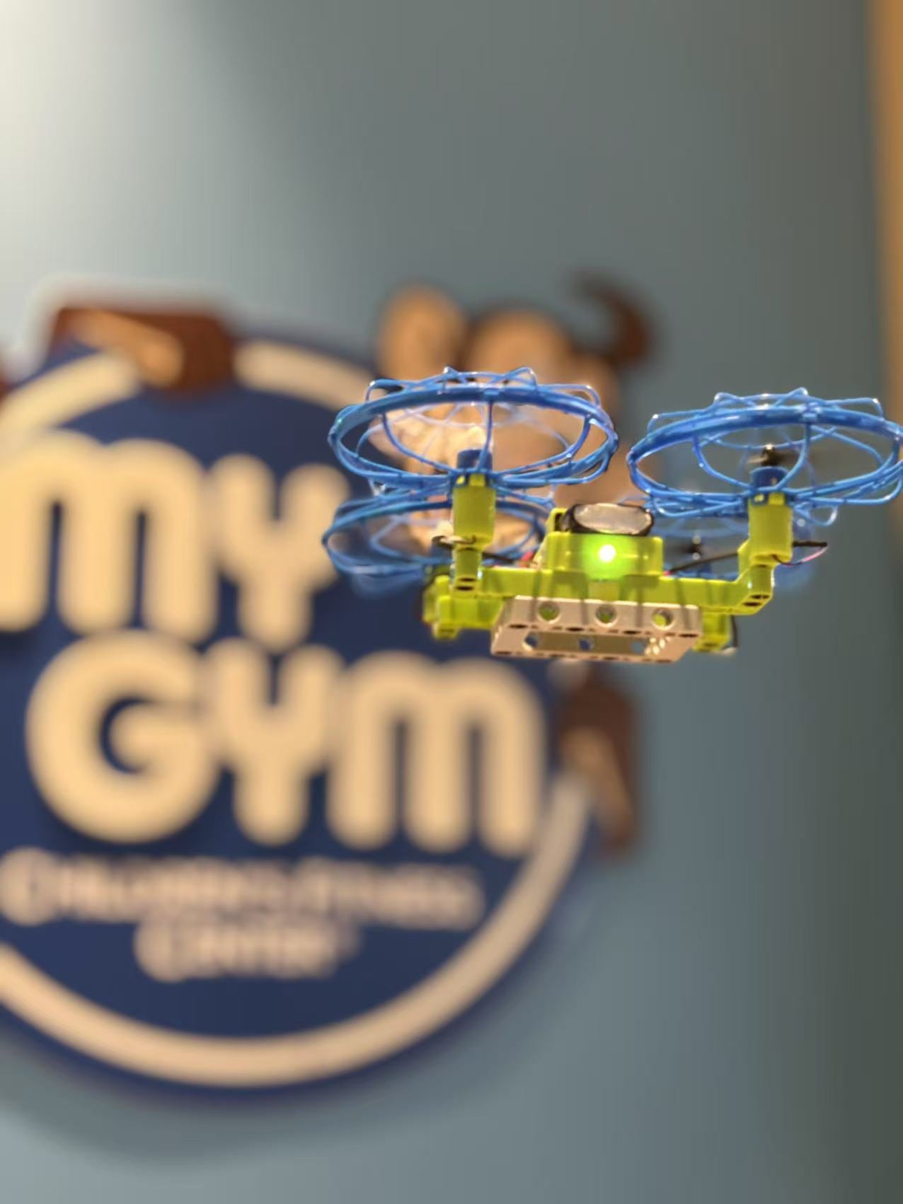 Close-up of a student-built drone flying in front of the classroom sign