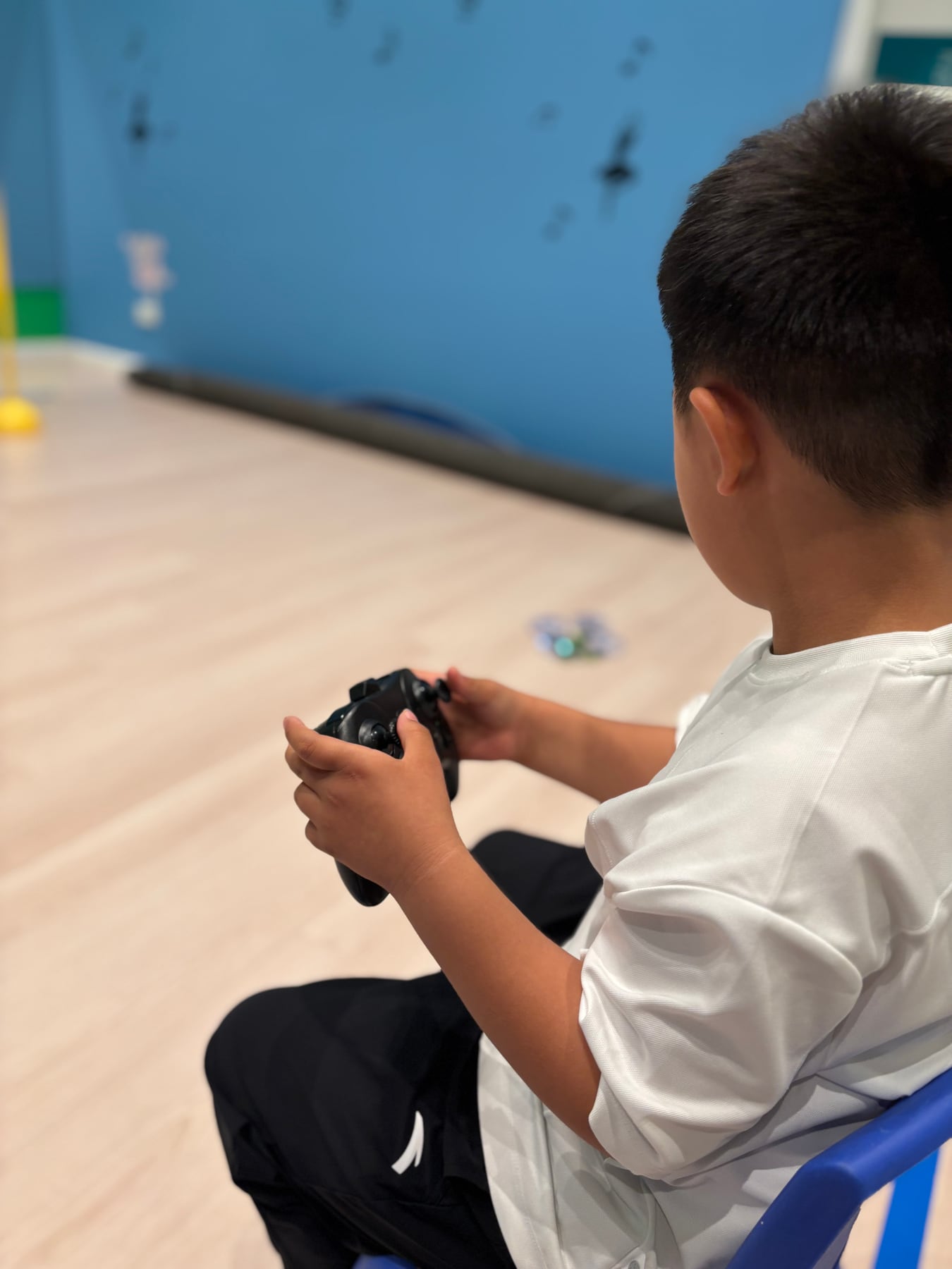A student using a controller to fly a small drone indoors