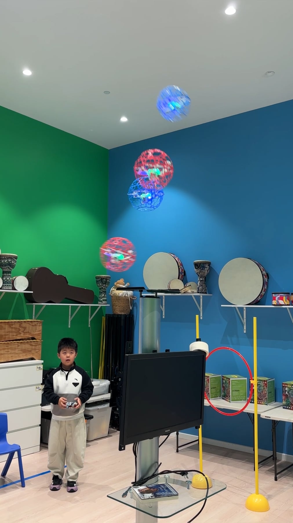 A student controlling several illuminated caged drones during class