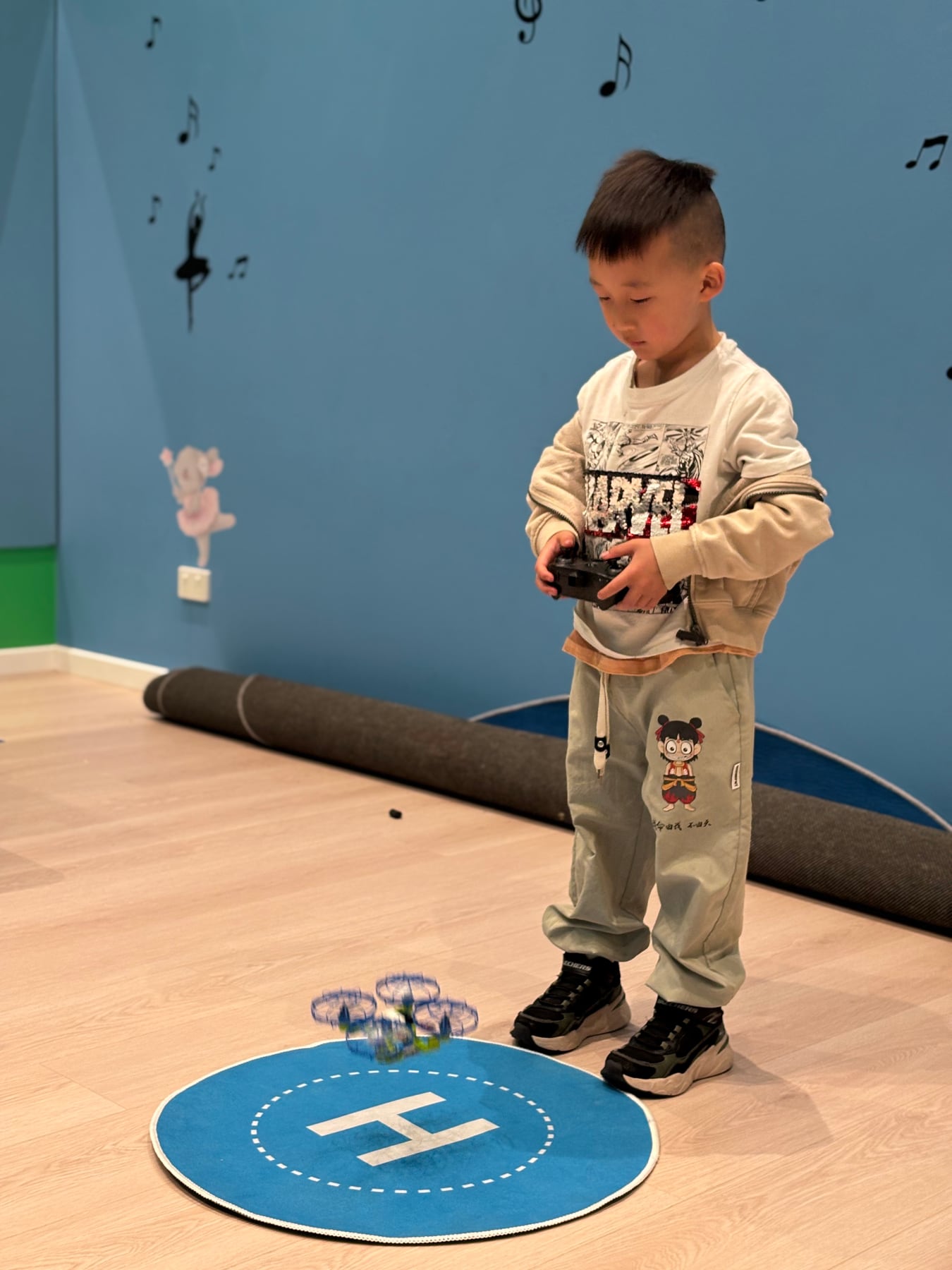 A student carefully landing a small drone on a marked landing pad